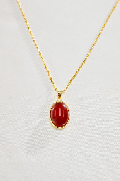 A gold-filled necklace with a red carnelian stone pendant, displayed against a white background. By DBL Jewelry