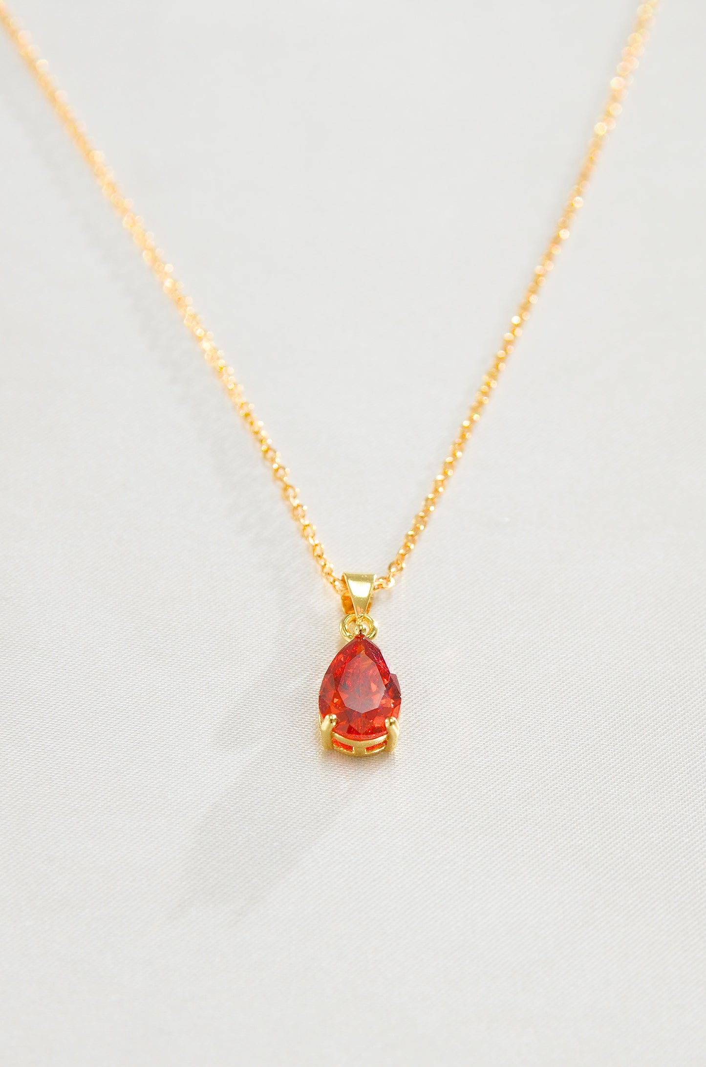 A gold-filled necklace with a teardrop-shaped red pendant, representing a Carnelian love amulet. by DBL Jewelry