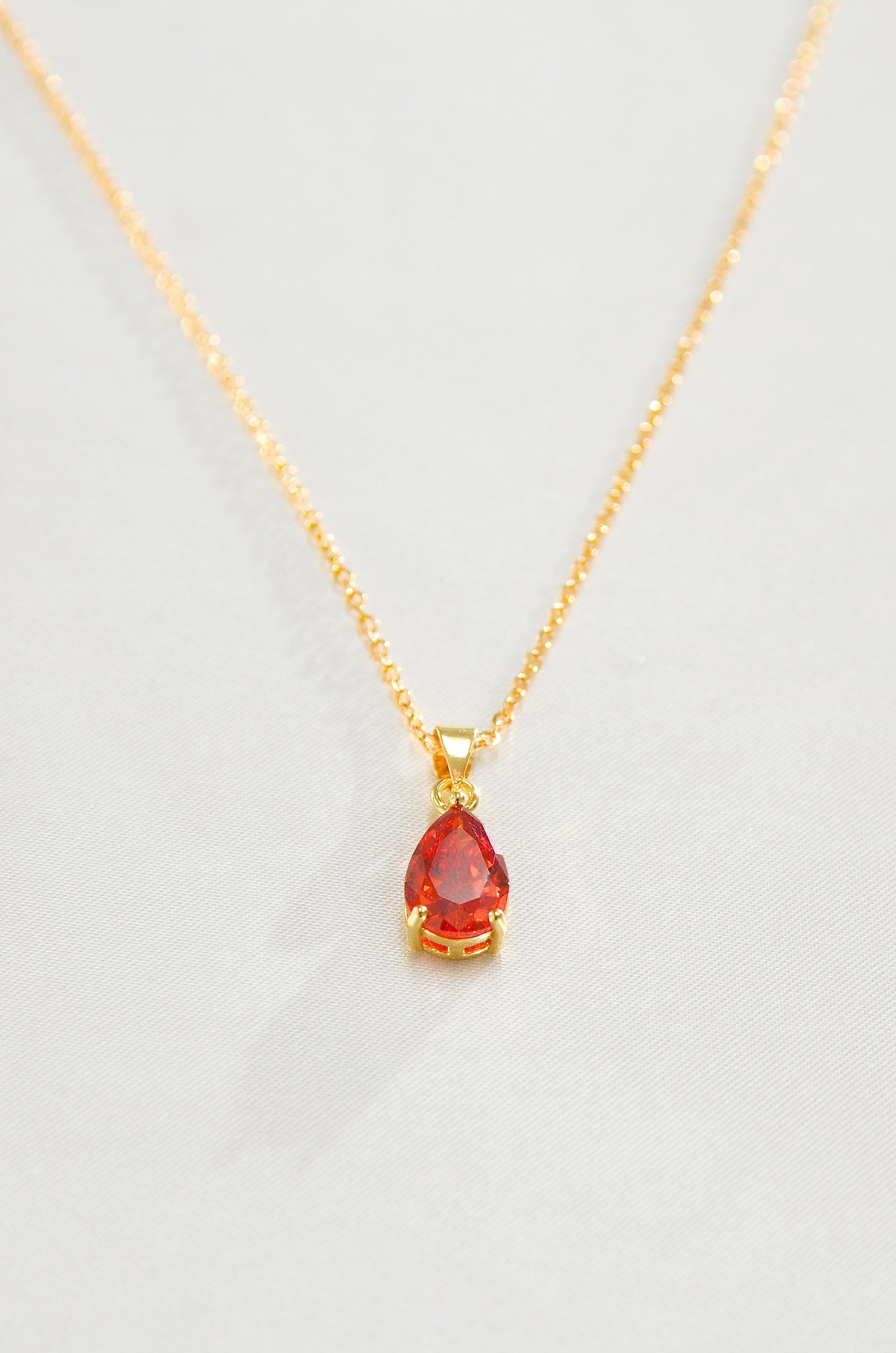 A gold-filled necklace with a teardrop-shaped red pendant, representing a Carnelian love amulet. by DBL Jewelry