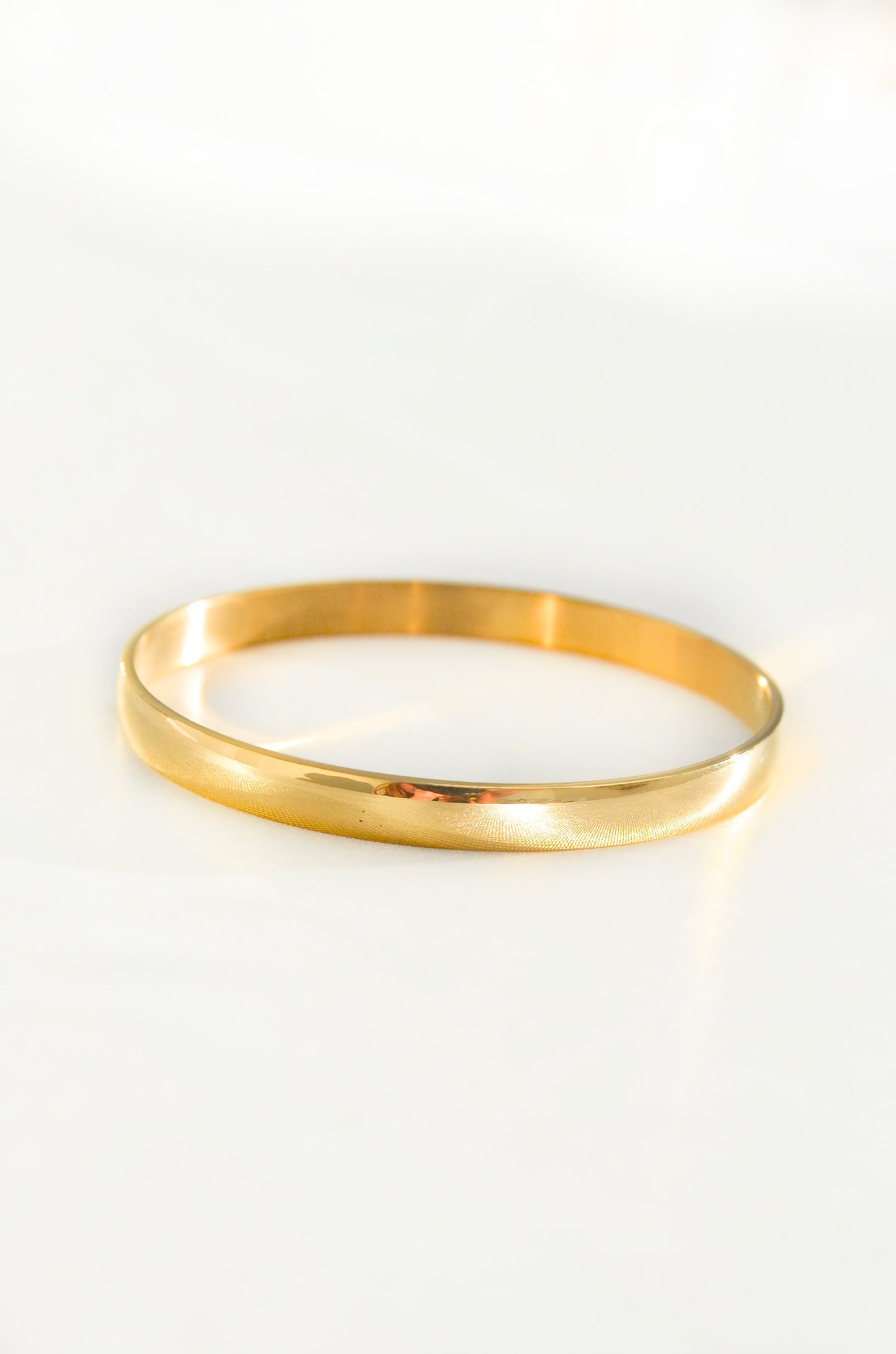 A single 18K PVD Gold Plated Bangle bracelet on a white background. By DBL Jewelry