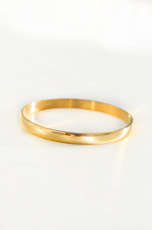 A single 18K PVD Gold Plated Bangle bracelet on a white background. By DBL Jewelry