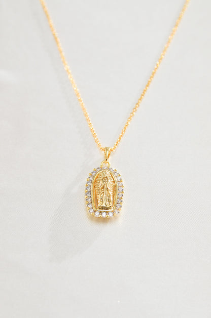 A gold-colored necklace featuring a pendant with the image of the Virgin Mary surrounded by diamond stones. By DBL Jewelry