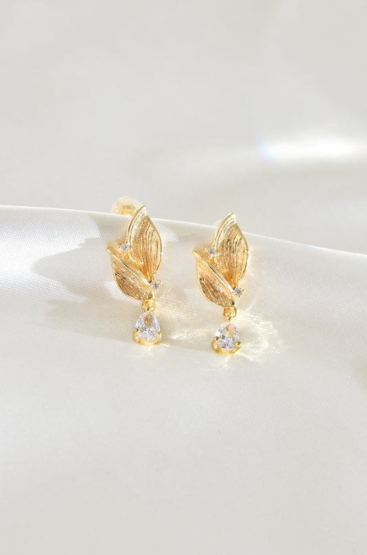 A pair of gold-filled leaf-shaped earrings with a fairy motif, featuring small clear stones at the bottom. By DBL Jewelry