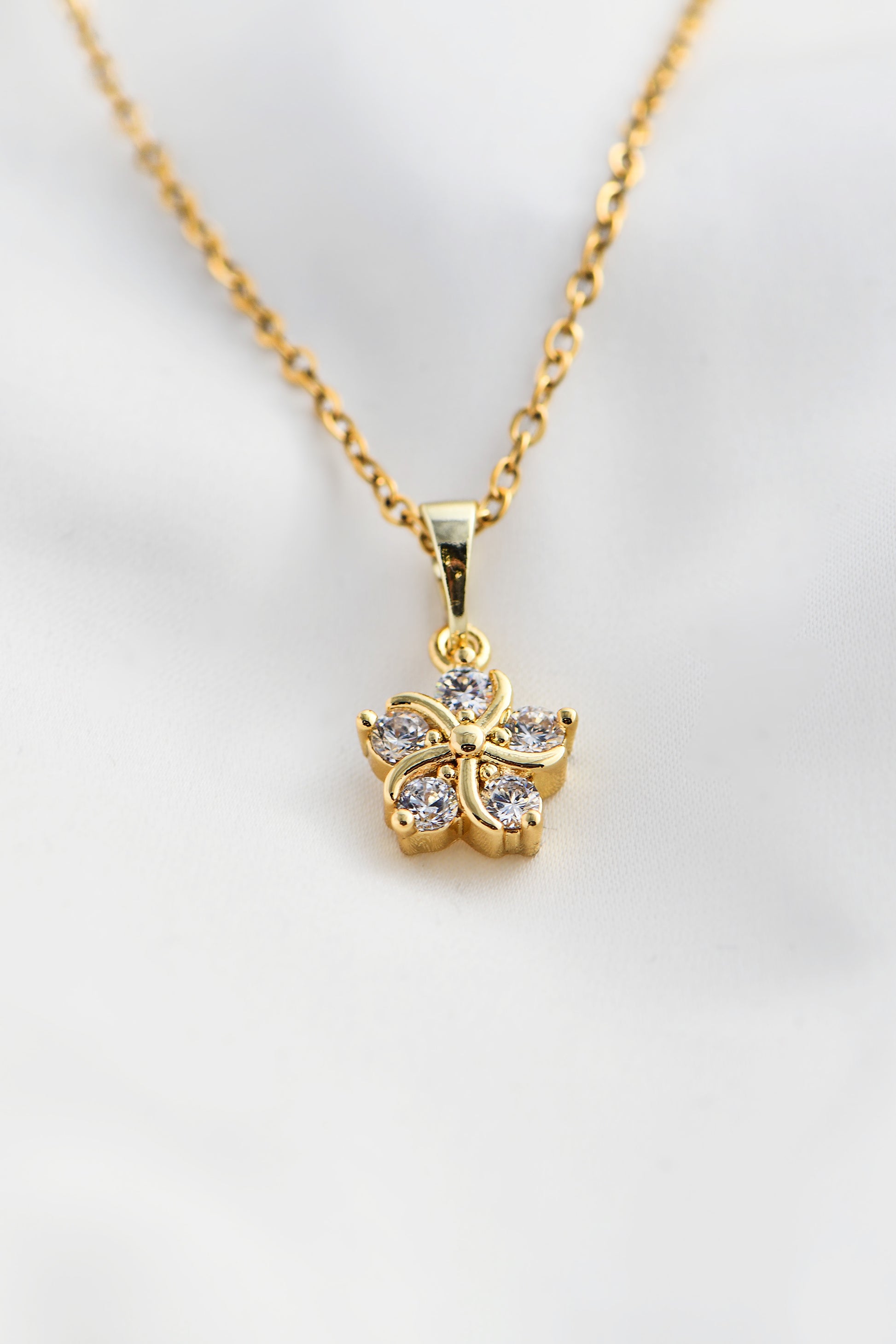 Gold necklace with a butterfly pendant on a light gray background