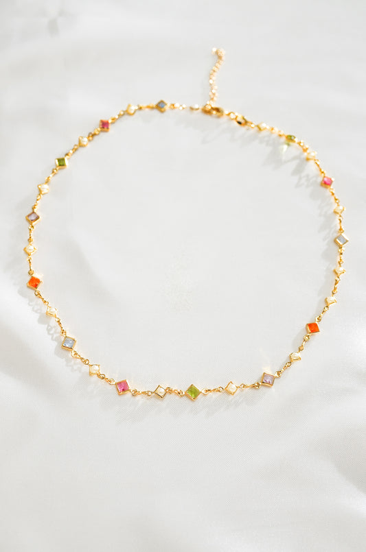 A gold-colored necklace with a series of multicolored crystal beads arranged in a chain link pattern.