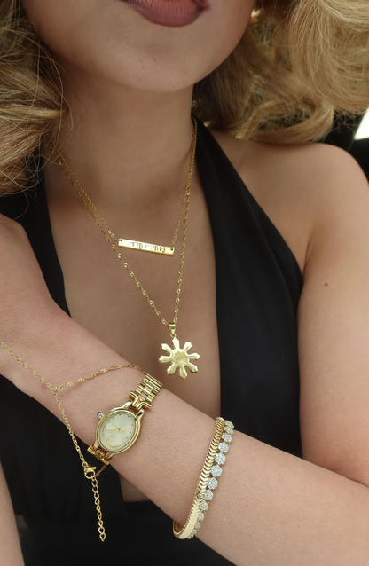 Close Up of Gold Mabuhay Sun Necklace layered with other gold necklaces and watch. By DBL Jewelry