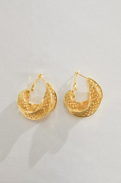A pair of gold hoop earrings with intricate woven pattern detailing, placed against a white background.