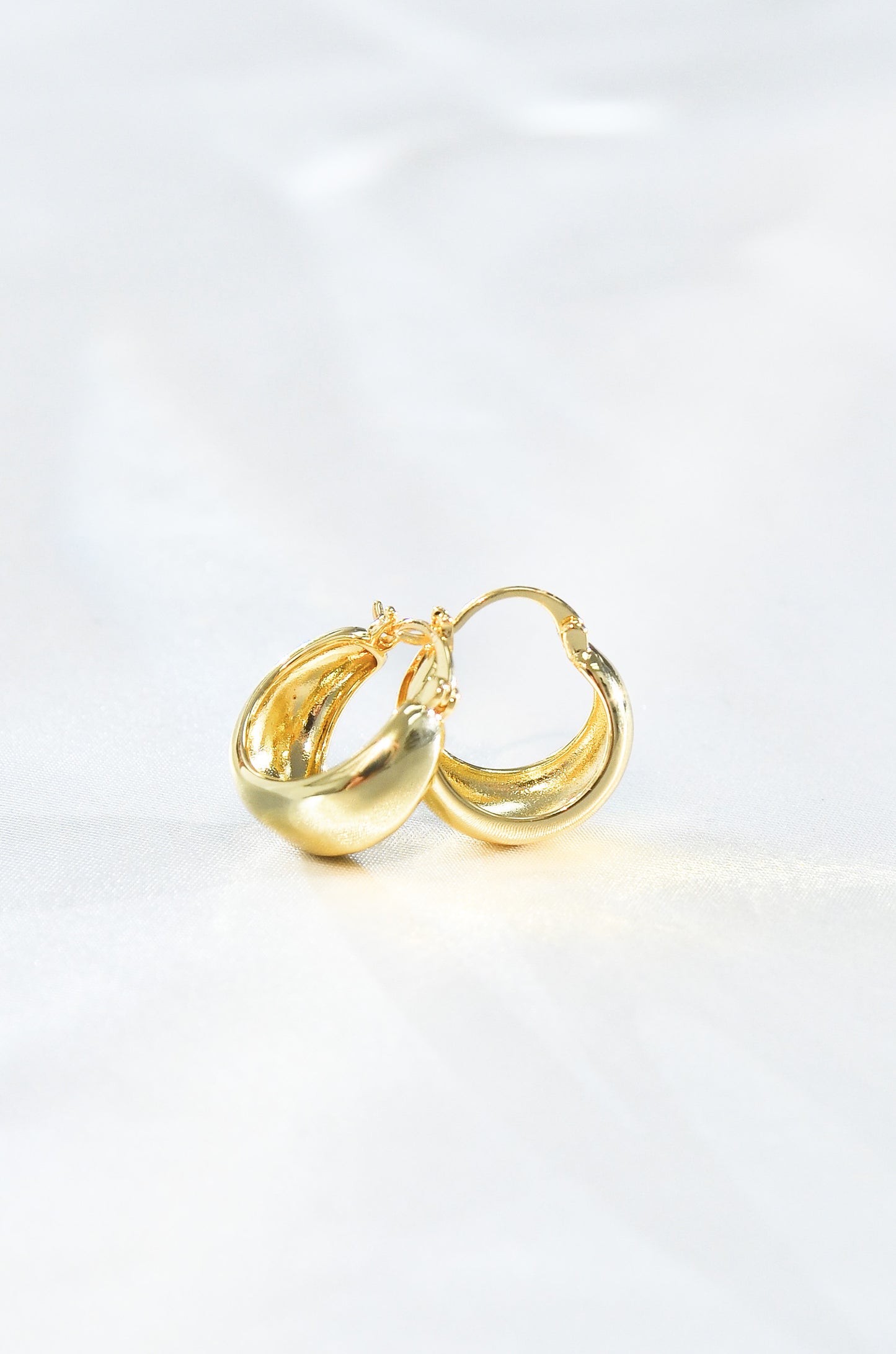 A pair of gold-filled mini dome hoop earrings on a white background. By DBL Jewelry