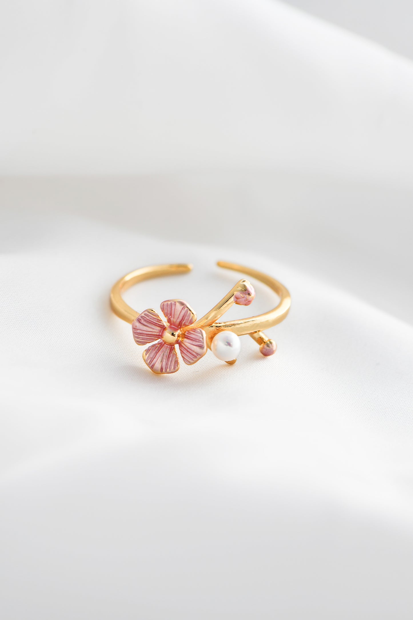 Gold ring with pink floral design and pearl on a white background. By DBL Jewelry