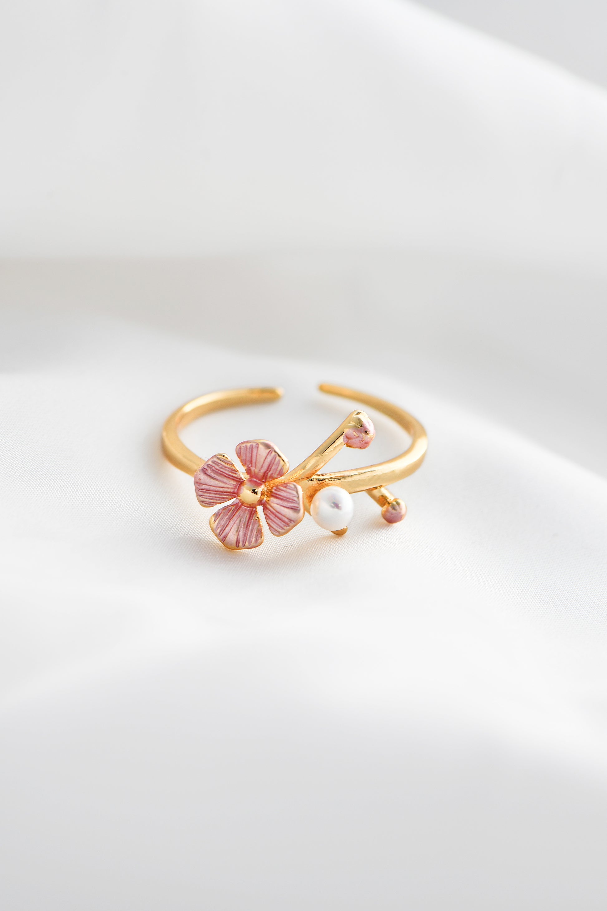 Gold ring with pink floral design and pearl on a white background. By DBL Jewelry