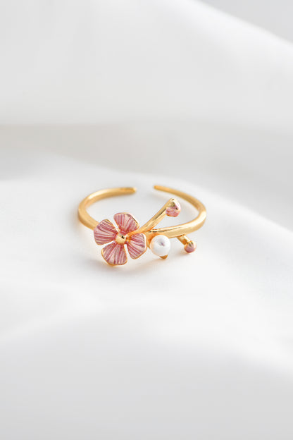 Gold ring with pink floral design and pearl on a white background. By DBL Jewelry